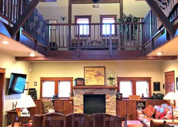 An open concept kitchen/living room with a fireplace sits below a wooden loft area.