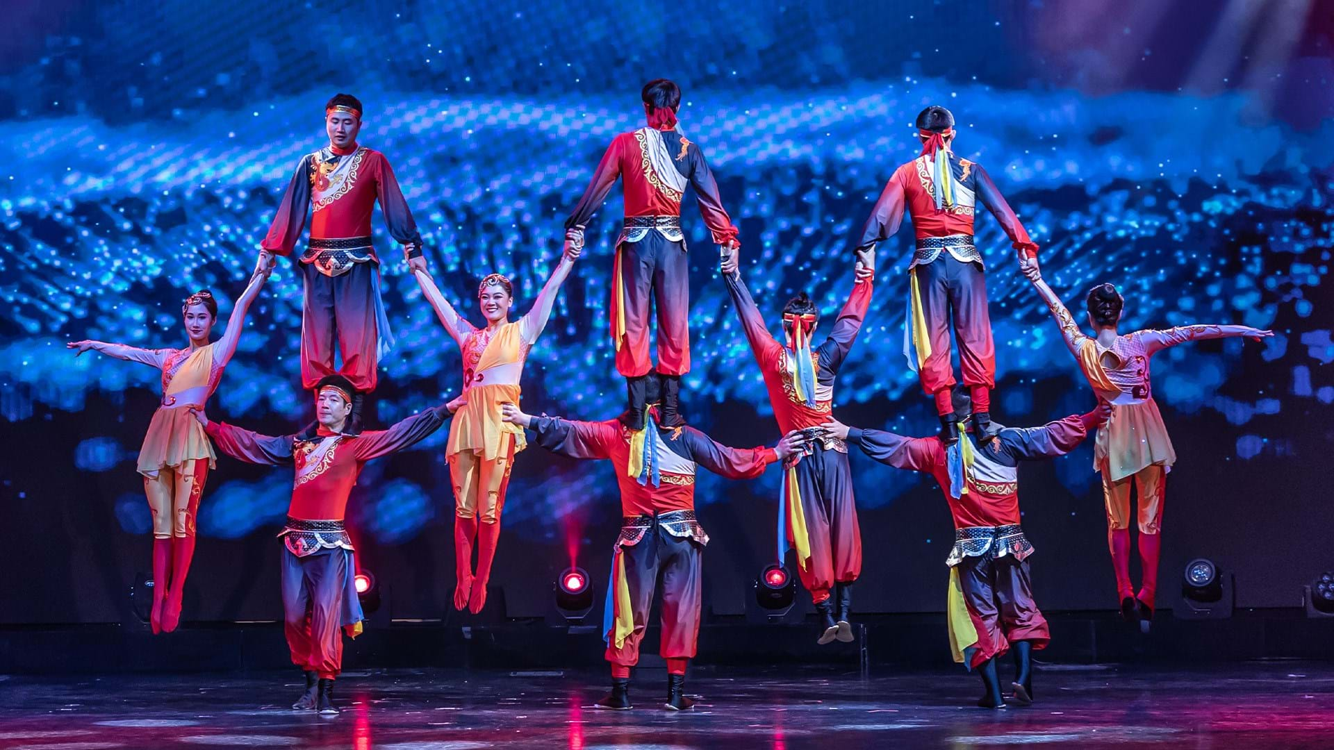 acrobatic circus performers wearing red perform a counterbalance trick