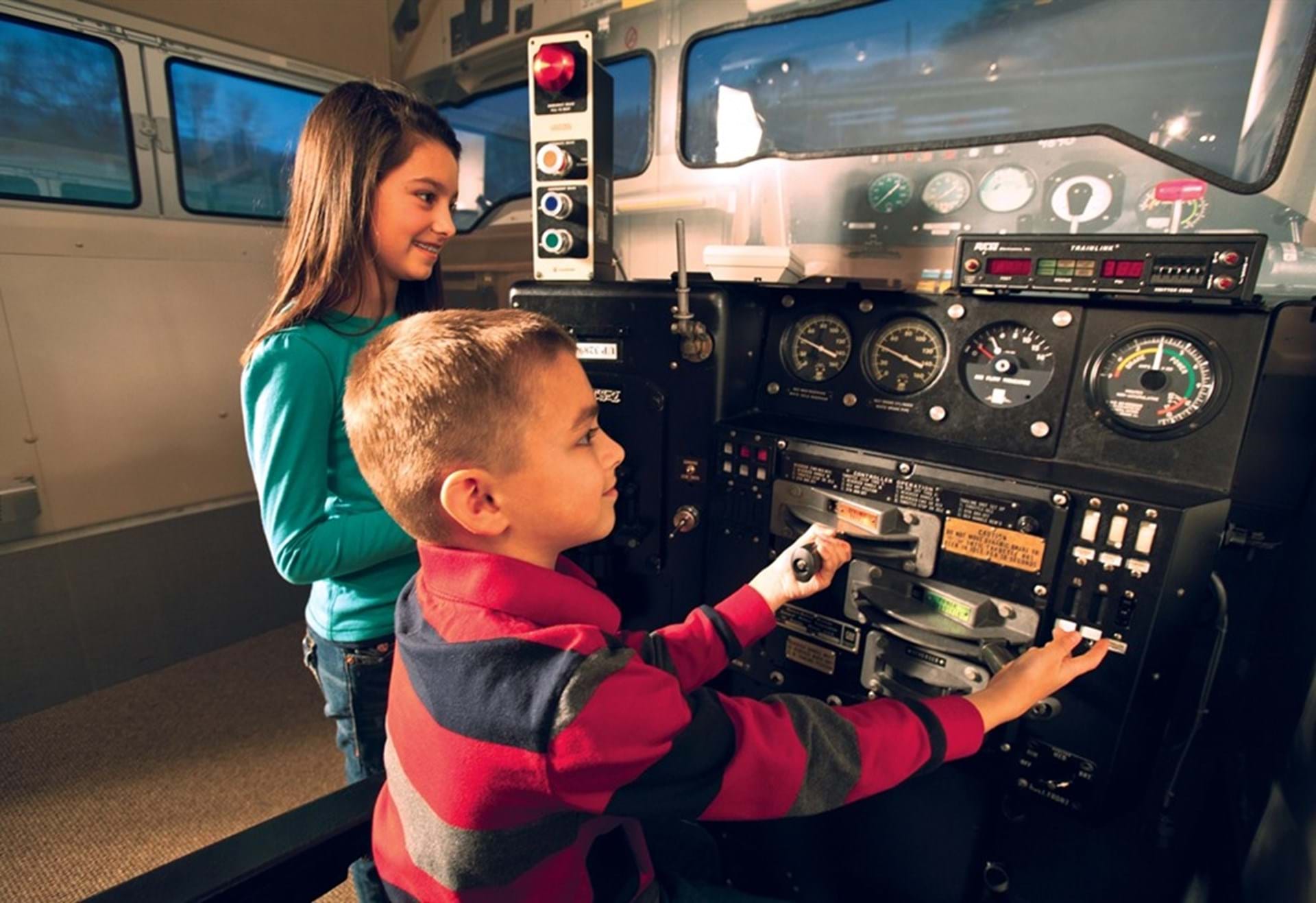 Two children operate the locomotive simulator. 